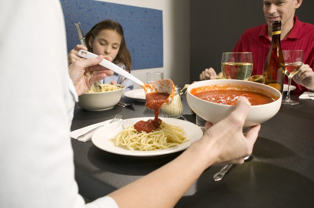 Woman pouring tomato sauce on pasta