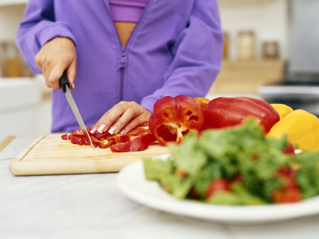 Person cutting red bell pepper, mid section