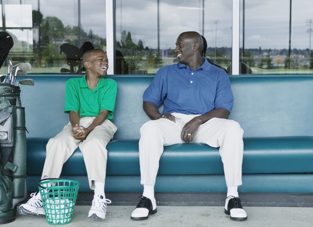 Father and son putting on golf shoes at a golf course