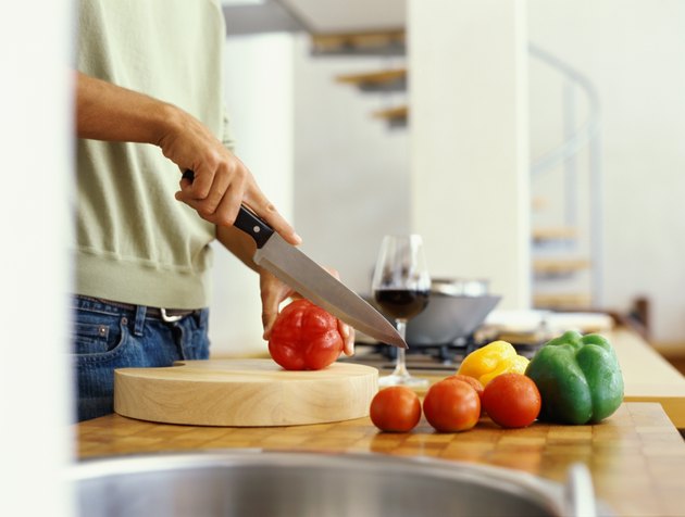 mid section view of a man cutting red bell pepper in the kitchen