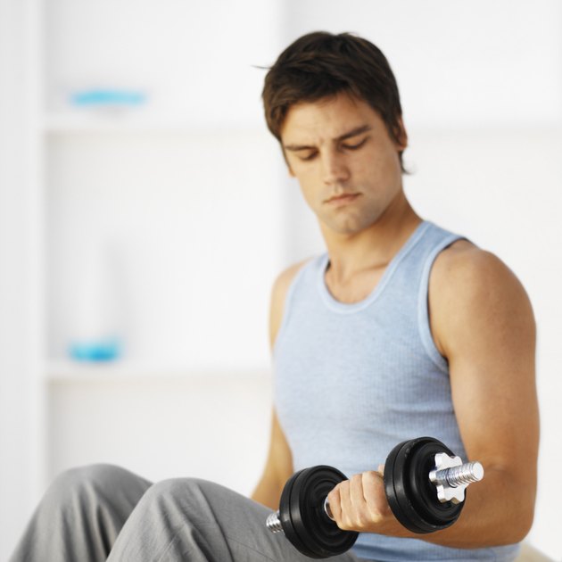 Close-up of young man lifting dumbbell