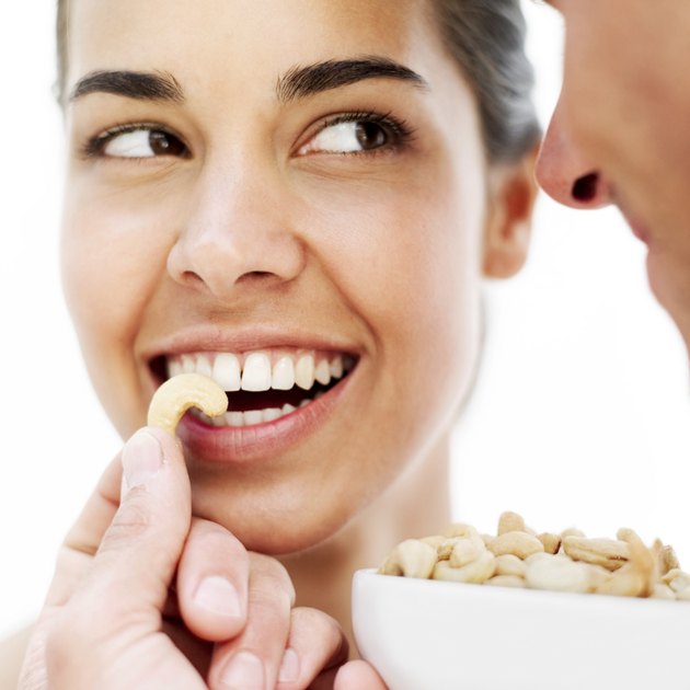 young man feeding a young woman cashew nuts