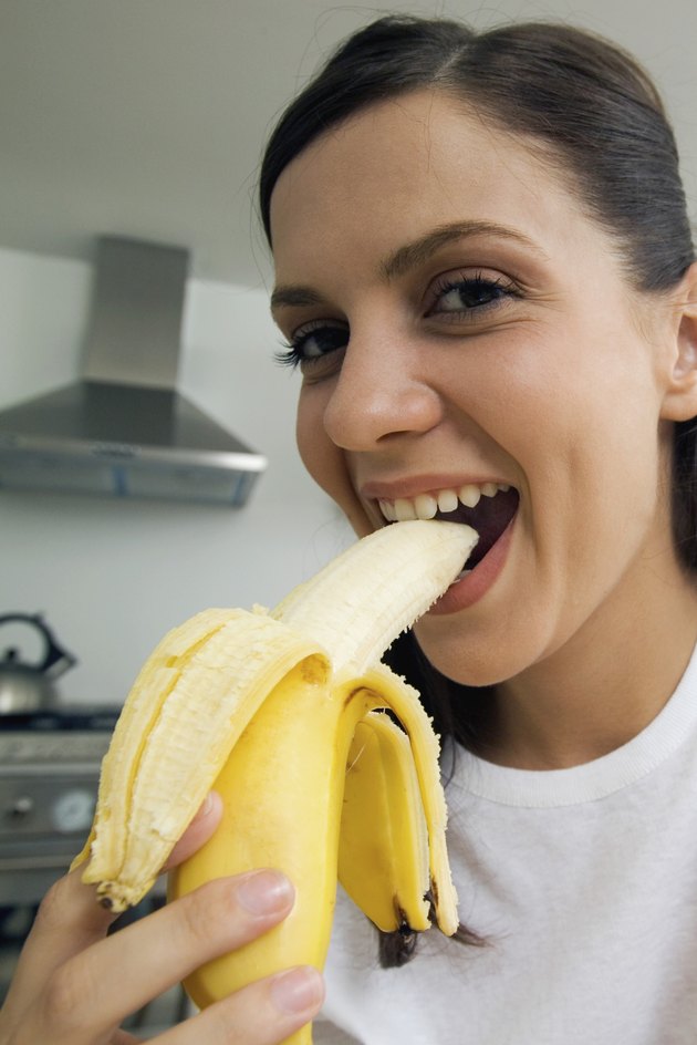 Close-up of young woman eating banana, low angle view, selective focus