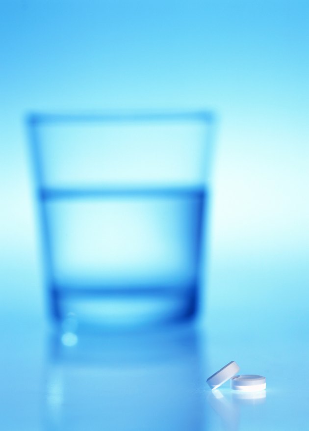 close-up of tablets lying beside a glass of water