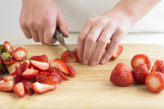 Cutting stawberries on a chopping board, close up