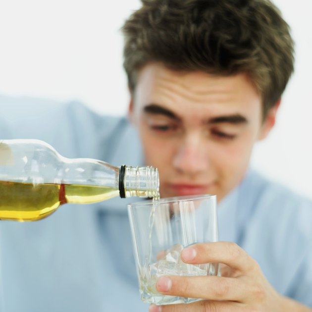 close-up of a teenage boy pouring wine from a bottle into a glass