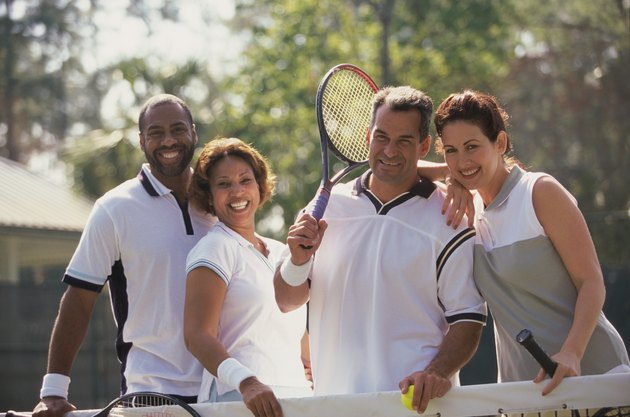 Portrait of two mid adult couples smiling on a tennis court