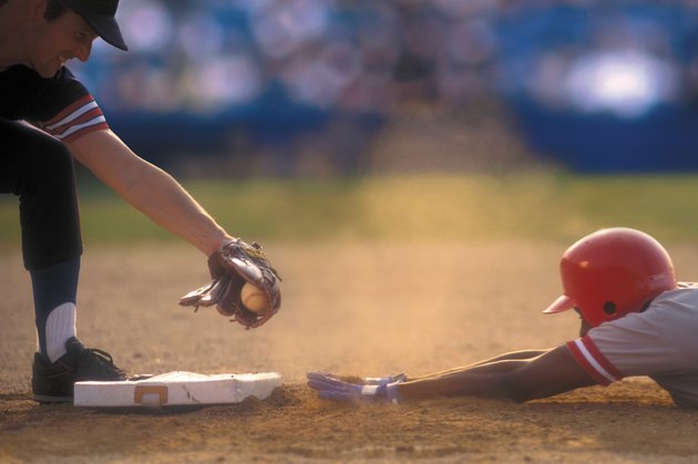 Baseball player sliding into base as baseman tags him
