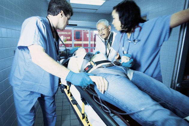 Doctors and nurses assisting patient on gurney
