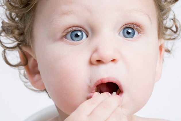 Head shot of toddler eating with surprised expression