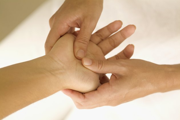One person's hand inside another's, with fingers pressing on palm