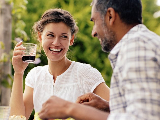 Couple dining outdoors, woman looking at man, laughing