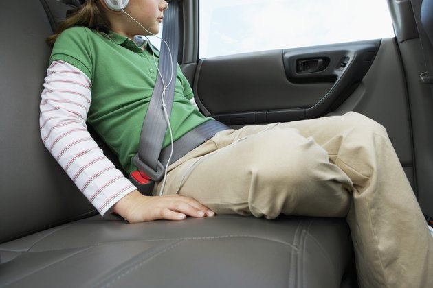 Girl (6-8 years) sitting on rear seat of car, close-up, side view