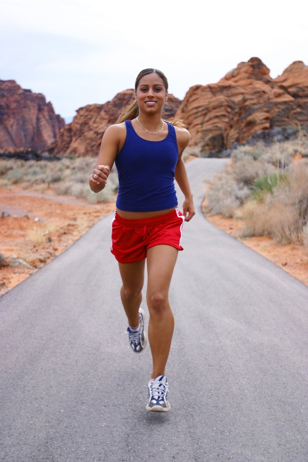 shot of a young ethnic female athlete as she runs through a rural red rock setting