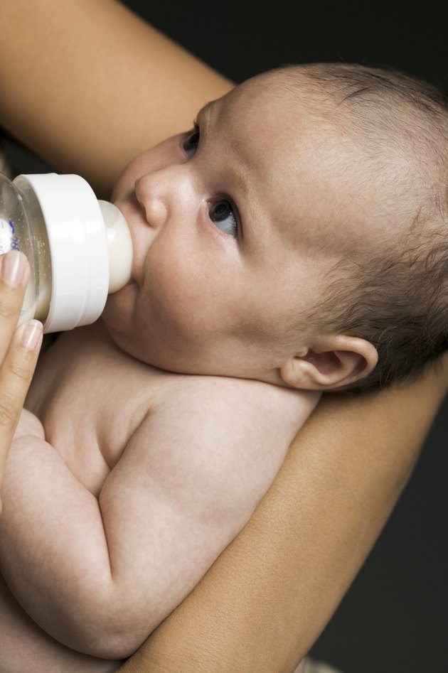 relationship portrait of a young mother as she feeds her newborn baby