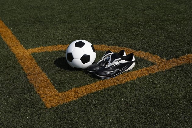 Soccer ball and cleats in corner of soccer pitch, elevated view