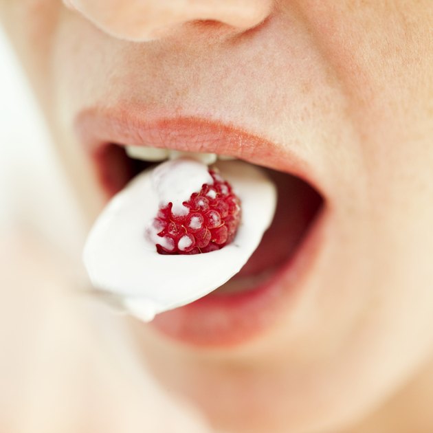 Close-up of a woman's mouth with a spoonful of yogurt in it
