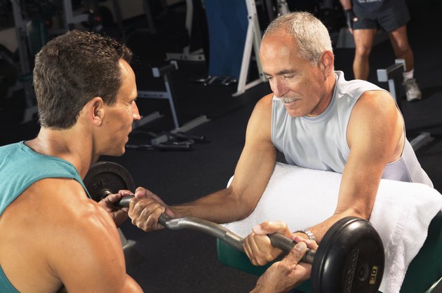 Mature man weight training with male fitness instructor