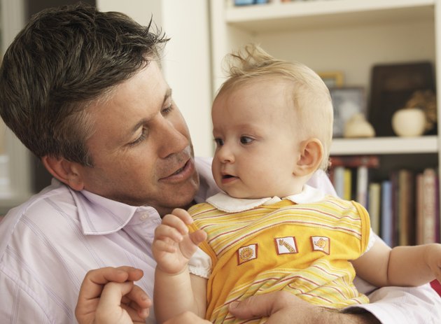 Father holding baby daughter (3-6 months) in living room