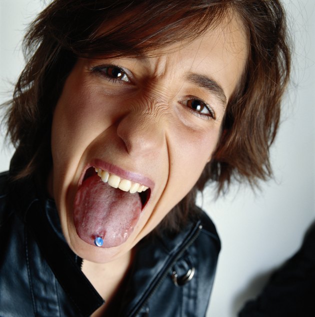 Young man sticking out pierced tongue, close-up