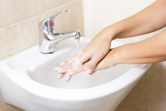 Woman washes with running water and soap hands