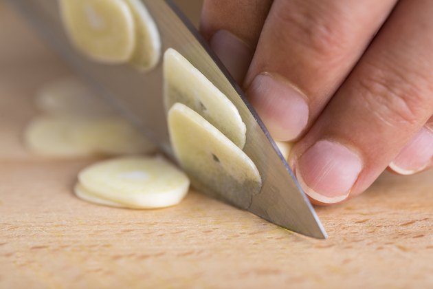 Chef slicing garlic cloves