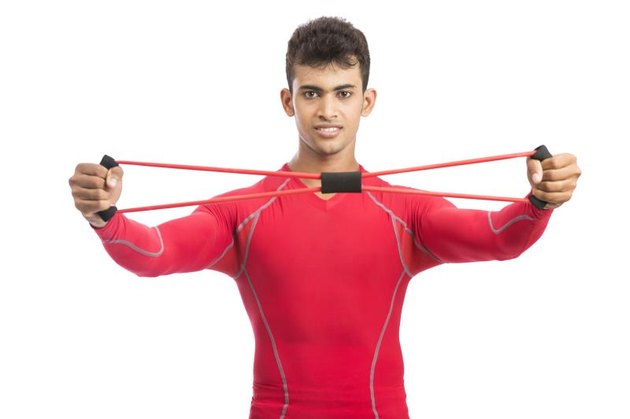 Handsome guy working out with rubber band over white background