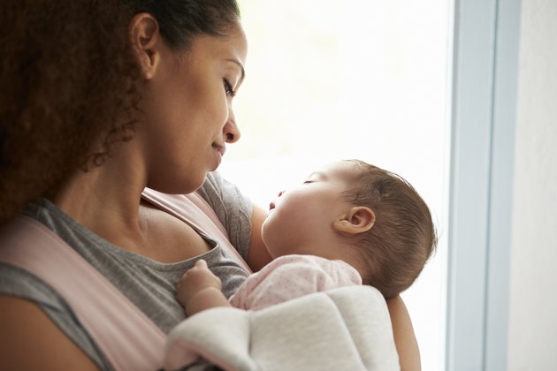 Close Up Of Mother Cuddling Baby Daughter At Home