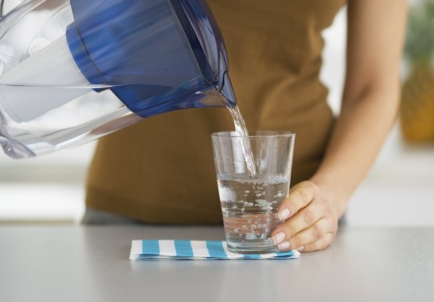 Closeup on housewife pouring water into glass