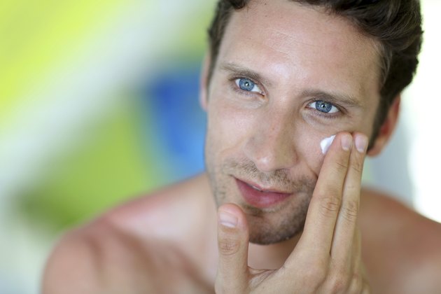 Portrait of man applying cream on his face