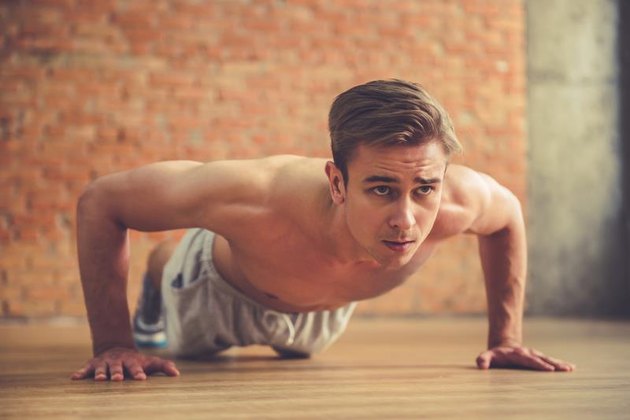 Handsome sportsman is doing push ups while working out in modern fitness hall