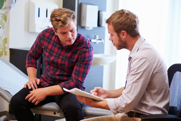 Male Patient And Doctor Have Consultation In Hospital Room