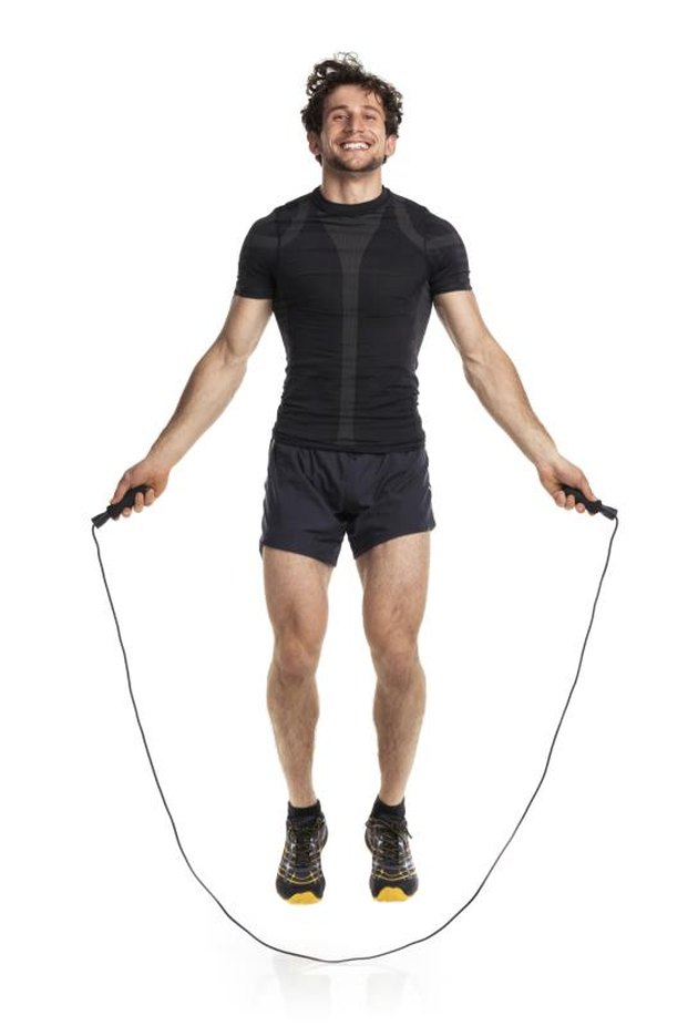 Athletic attractive man jumping on a rope on the white background