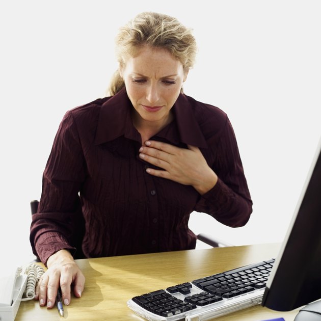 businesswoman sitting in front of a computer with her hand on her chest