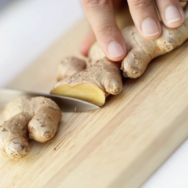 close-up of a person cutting ginger on a cutting board