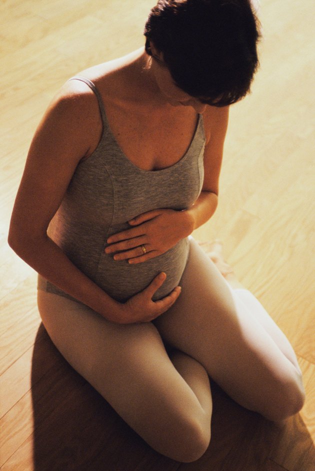 High angle view of a pregnant woman touching her abdomen