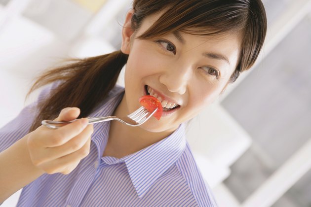 Young Woman Eating Tomato