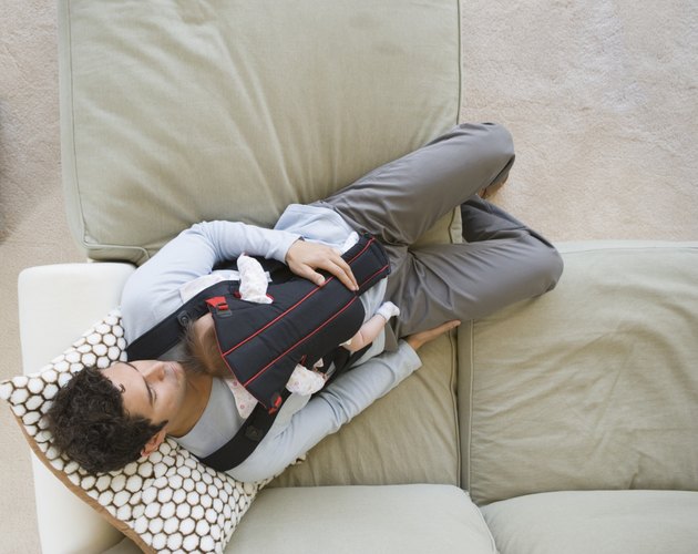 Hispanic father sleeping on sofa with baby
