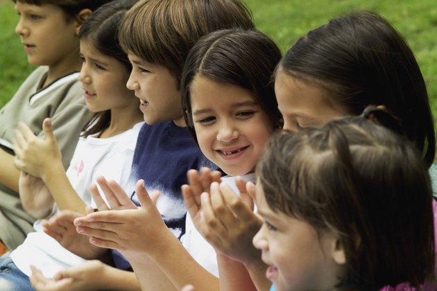 Six children outside clapping hands, close-up