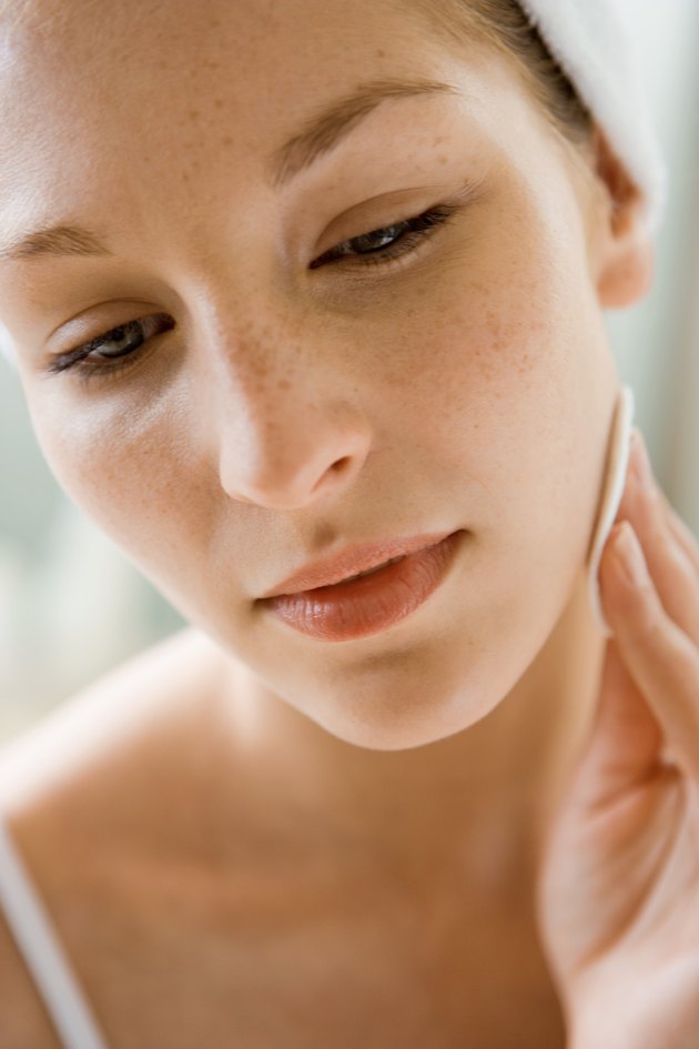 Woman rubbing cotton pad on her face