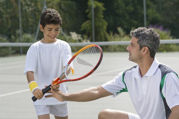 Man teaching boy to play tennis