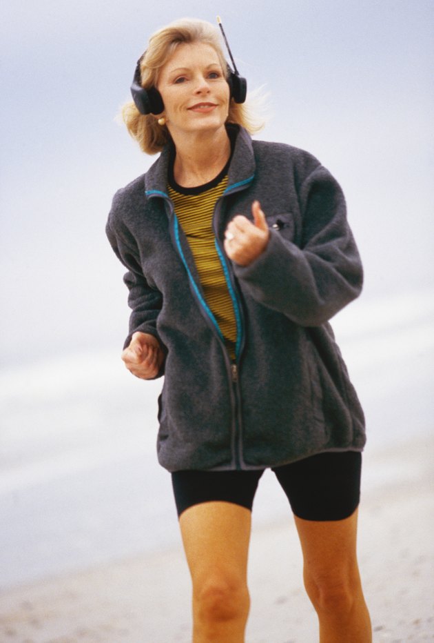 Woman running along beach, wearing headphones