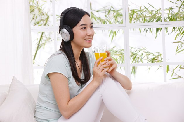 Young woman drinking juice and listening to music