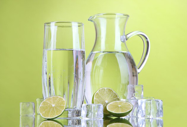 Glass pitcher of water on green background