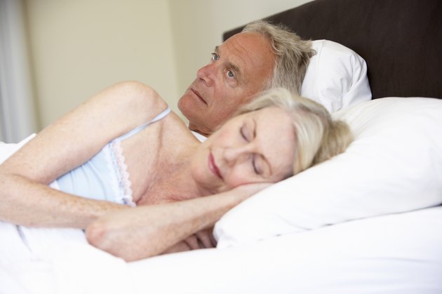 Senior Woman In Bed With Worried Husband