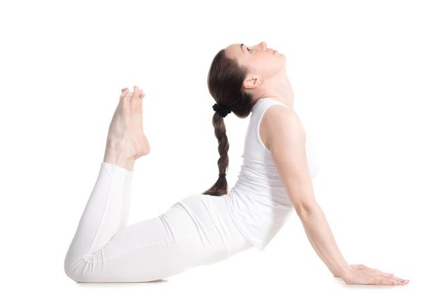 Sporty beautiful young woman in white sportswear doing King Cobra Pose, Raja bhudjangasana, studio full length side view, isolated