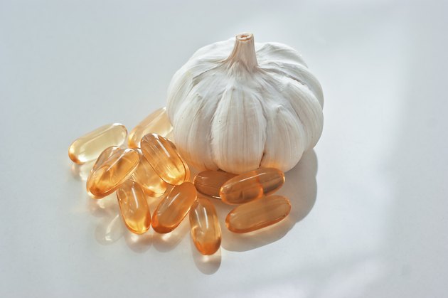 garlic oil capsules on a white reflective surface