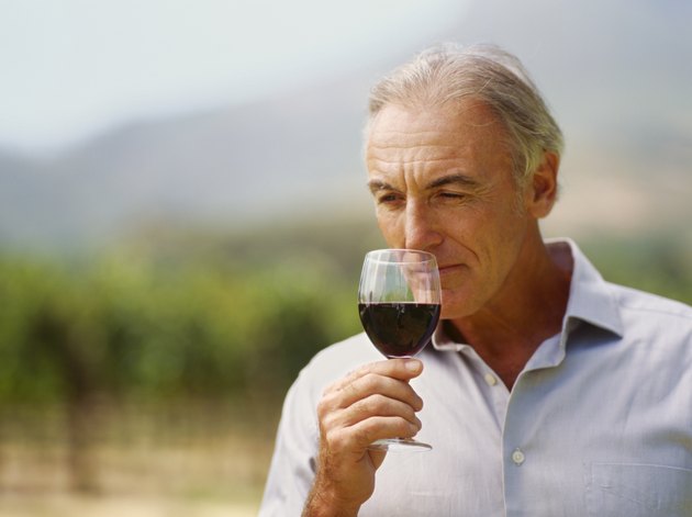 close-up of a mature man sniffing a glass of red wine