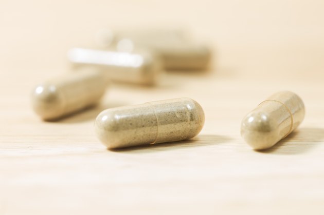 Herbal medicine pills on wood board.