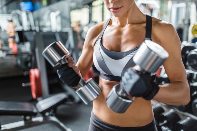 Female athlete with barbells exercising in gym